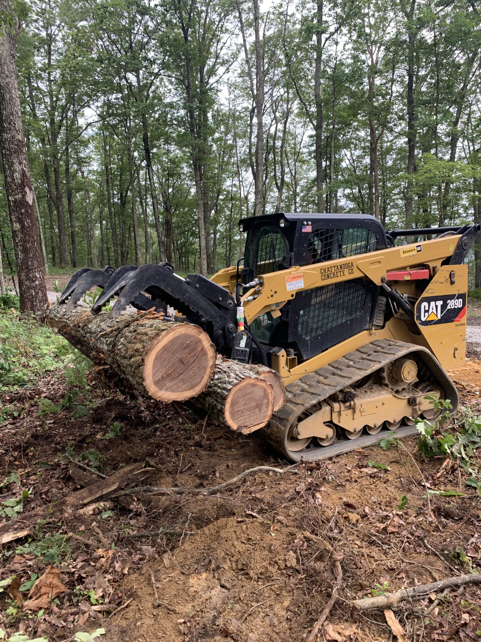Excavating tractor grappling logs