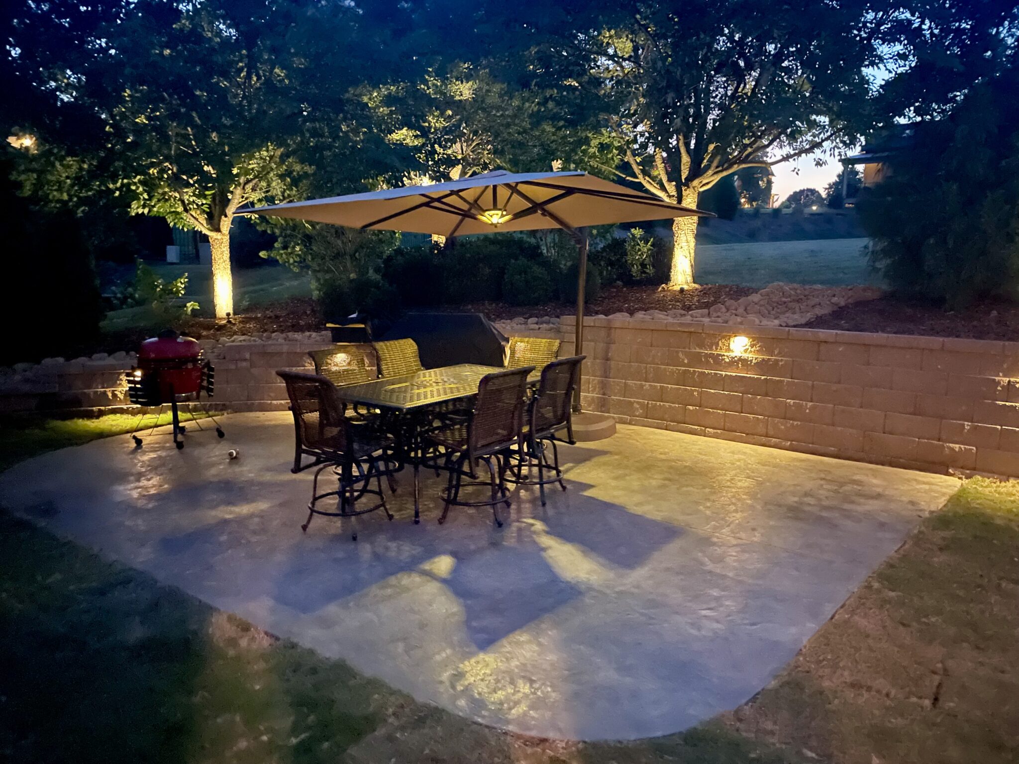 Backyard patio at night with retaining wall in backgrounds with lights